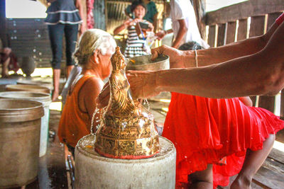 Cropped hand of man washing buddha statue