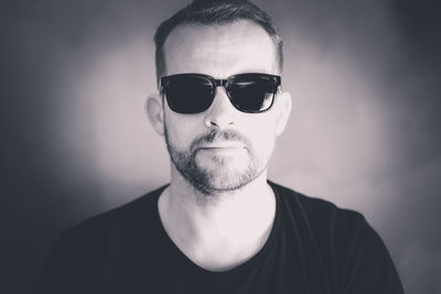 Portrait of man wearing sunglasses against gray background