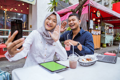 Portrait of young woman using mobile phone while sitting on table