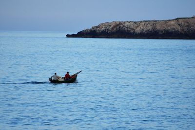 People in boat sailing on sea against clear sky