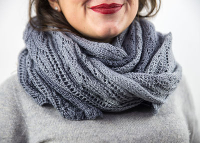 Midsection of woman wearing knitted scarf and sweater against white background