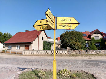 Road sign by building against clear sky