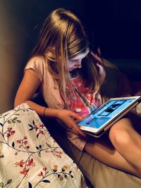 Midsection of woman using mobile phone while sitting on bed