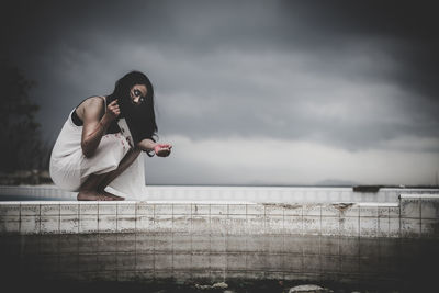 Woman standing by railing against sky