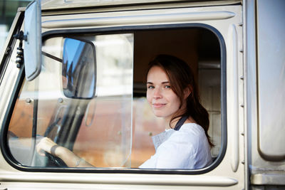 Portrait of smiling young female owner driving food truck in city