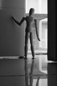 Woden mannequin standing behind the door, looking away