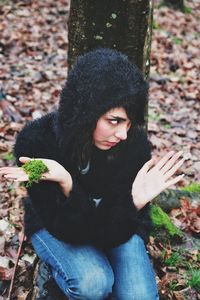 Teenage girl crouching in forest during autumn 