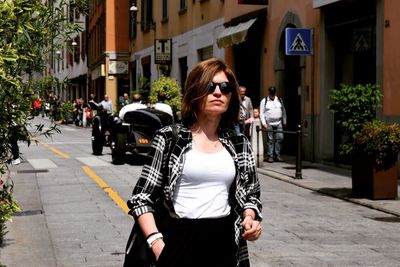 Young woman wearing sunglasses standing on street in city