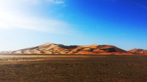 Sand dunes in desert against blue sky