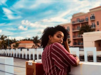 Portrait of woman standing against sky in city