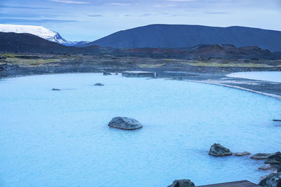 Scenic natural geothermal spa in blue lagoon against mountains during winter
