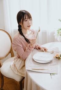 Portrait of young woman sitting on bed at home