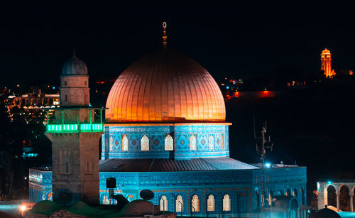 Illuminated mosque against sky at night