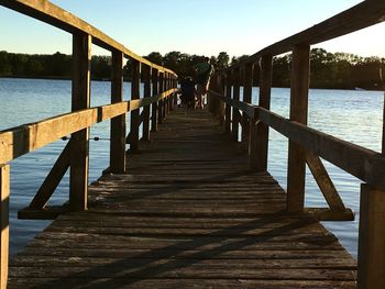 Rear view of pier over lake against sky