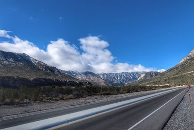 Road by mountains against blue sky