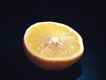 Close-up of orange slice on table against black background