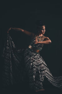 Woman looking at camera while standing against black background