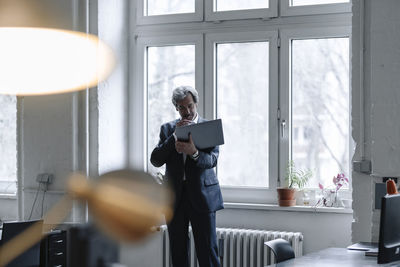 Senior businessman using laptop at the window in office