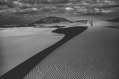 Shadow of man on sand at beach against sky