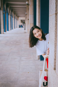 Portrait of happy woman standing against wall