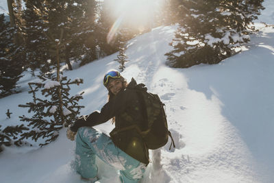 Young woman with backpack on snowy field during sunny day