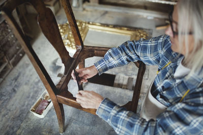 High angle view of craftsperson making wooden chair at workshop