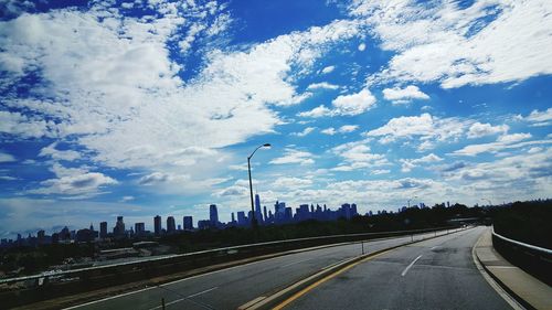 Road by buildings against sky