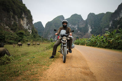 Full length of man riding motorcycle on road against mountains