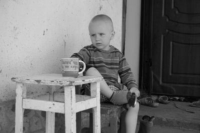 Boy sitting at table against wall