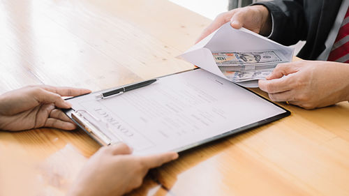 Midsection of man holding paper on table