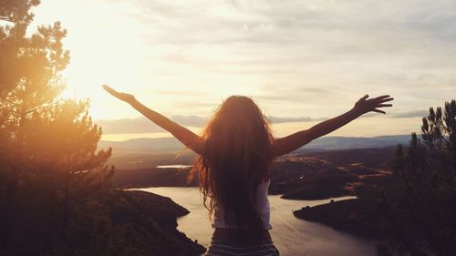 Rear view of woman with arms outstretched against sky