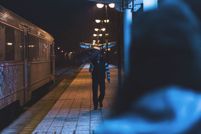 Train on illuminated railroad station platform at night