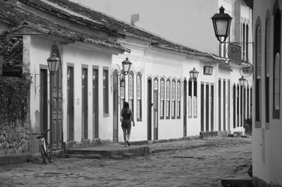 Rear view of woman walking on street against building