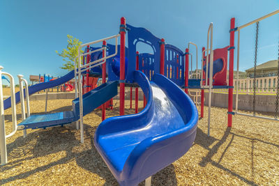 Empty playground against blue sky on sunny day