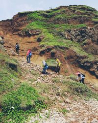 People walking on field by mountain against sky