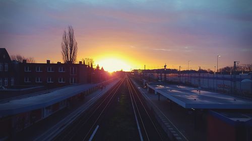 Railroad tracks in city against sky during sunset