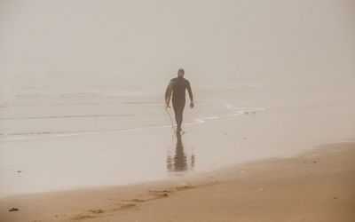 Surfer with surfboard walking on shore at beach
