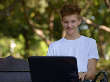 Portrait of teenage boy using mobile phone outdoors