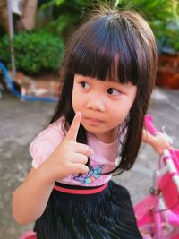 Cute girl with hand raised looking away while sitting outdoors