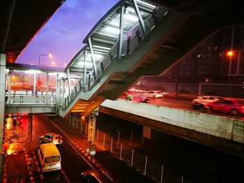 Train on illuminated bridge in city against sky at night