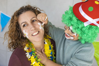 Mother painting her son's face like a clown