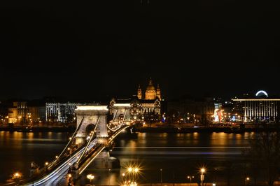 Illuminated bridge over river in city at night