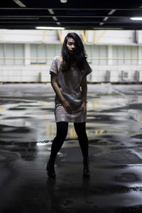 Full length of young woman standing on wet floor in parking lot