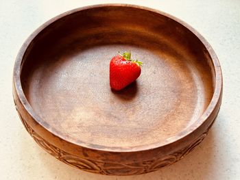 One strawberry in a circular wooden bowl. fresh, red, juicy, sweet, nutritious, summer fruit.
