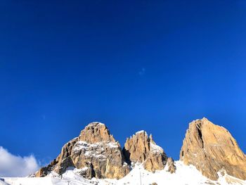 Low angle view of snowcapped mountains against blue sky