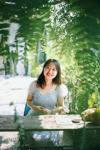 Portrait of young woman sitting on pier over lake