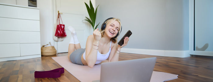 Portrait of young woman using mobile phone while sitting at home