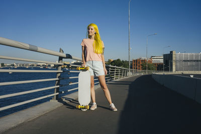 Full length of woman standing on railing against sky