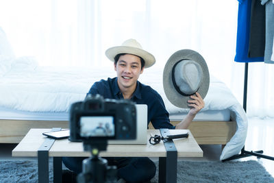 Portrait of young man photographing while sitting on table