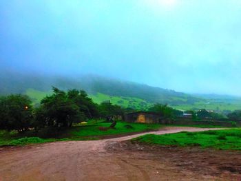 Road amidst field against sky